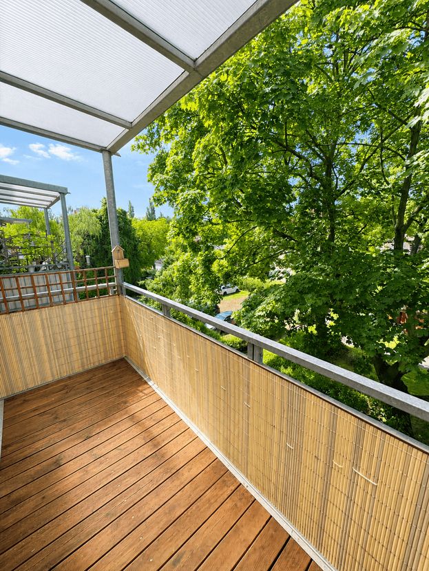 Balkon mit Holzdielen und Aussicht ins Grüne der Trenta Living Wohnung Reick